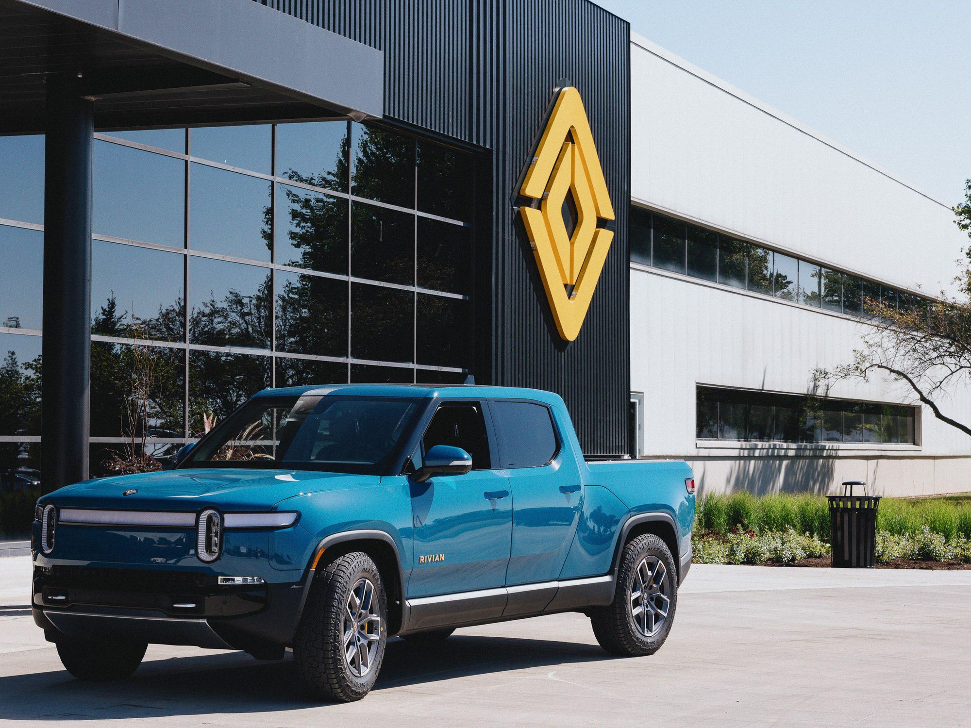 An R1T in Rivian Blue at the main entrance to the plant in Normal, IL.​