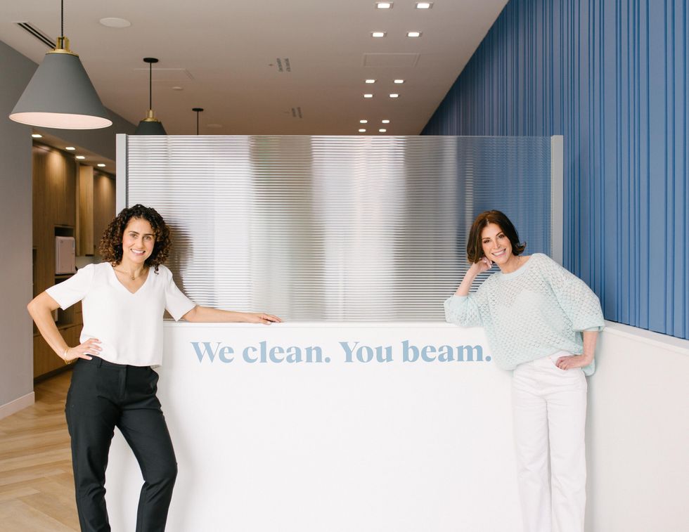 Carolyn Yashari Becher and Dr. Jamie Sands in front of a "we clean. you beam." sign