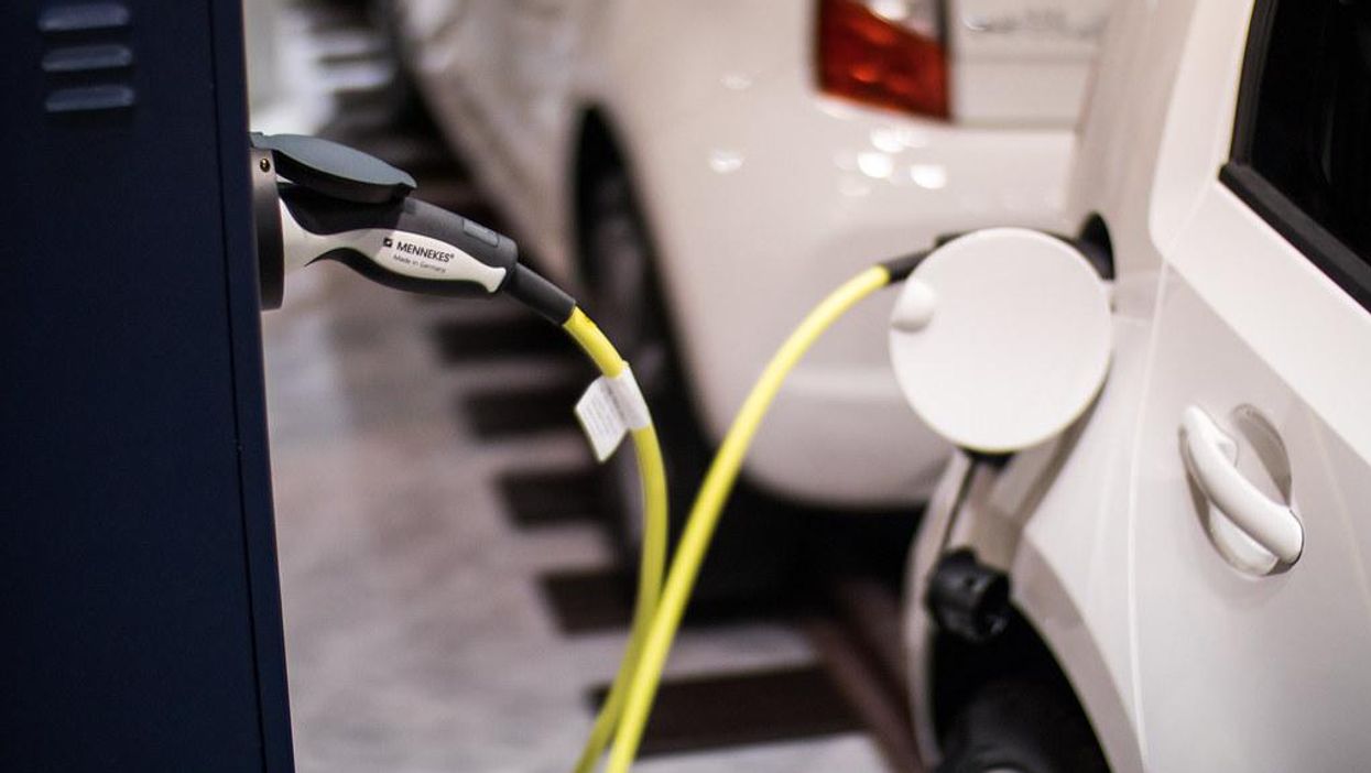 Electric vehicle charger plugged into white electric vehicle.