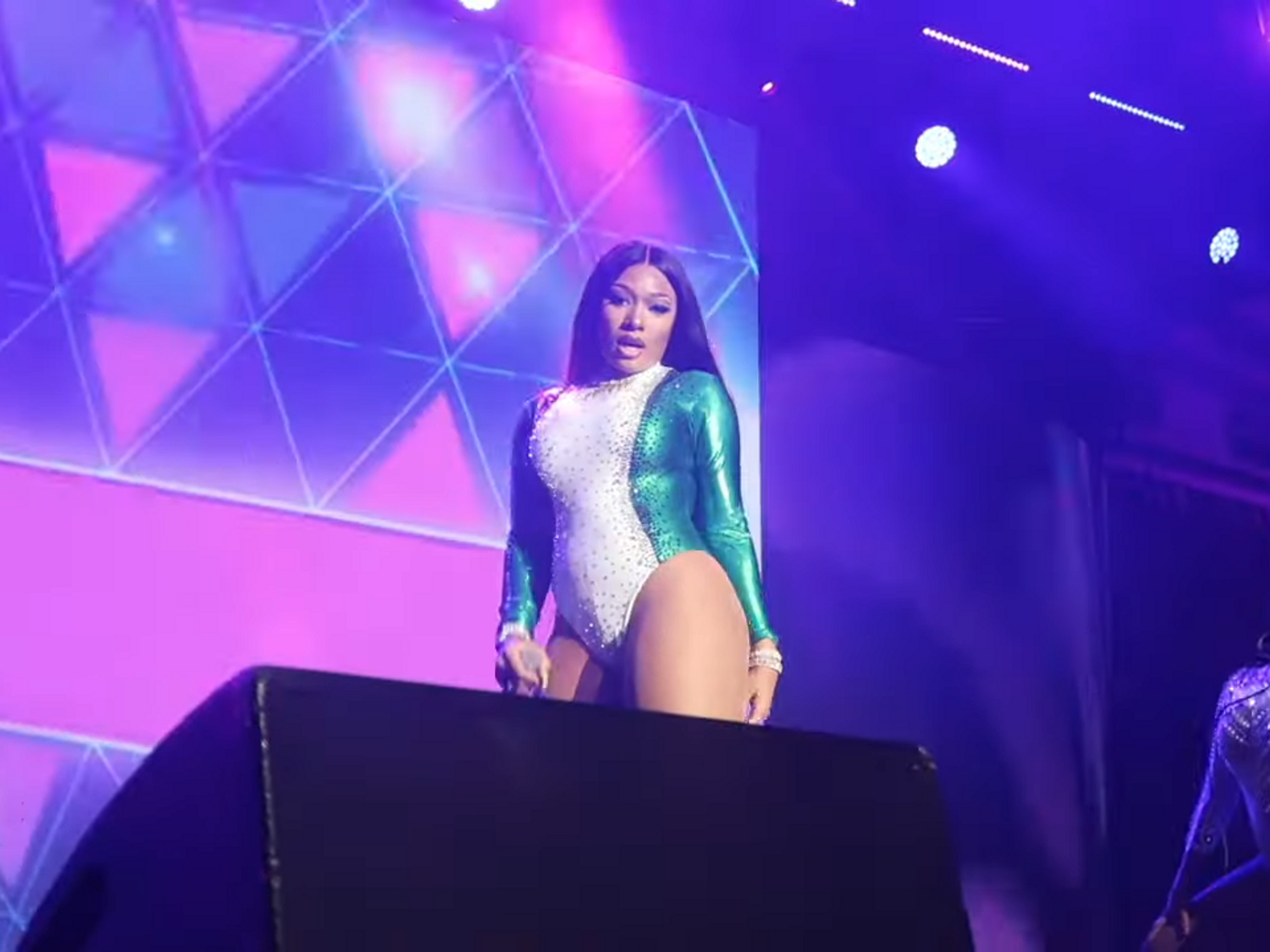 Megan Thee Stallion performing on stage in a blue and white leotard.