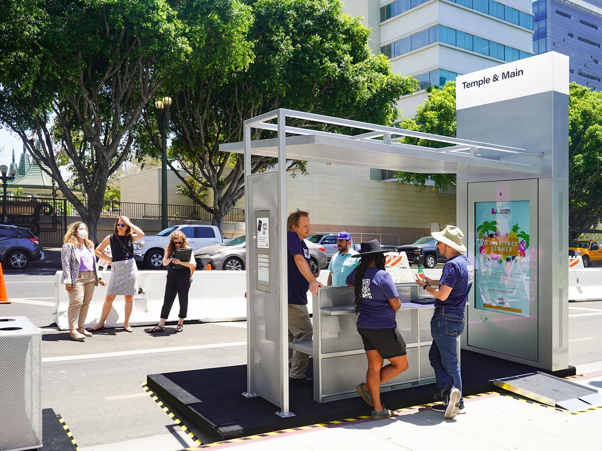 People standing at a Tranzito bus stop hub at the Temple & Main Bus stop.