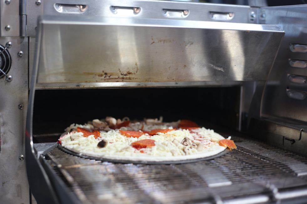 \u200bA pizza going into the automated oven.